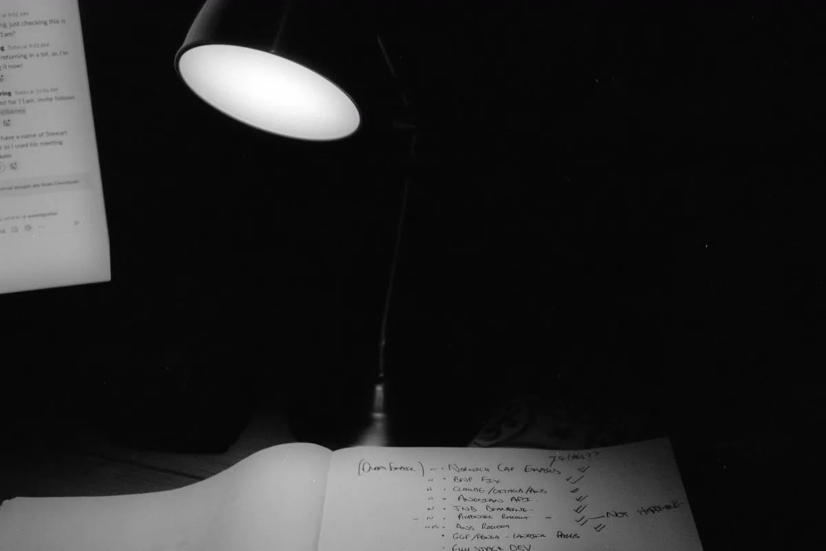 A notebook and pen under the glow of a desk lamp in an otherwise dark room, used to write worries down before bed.